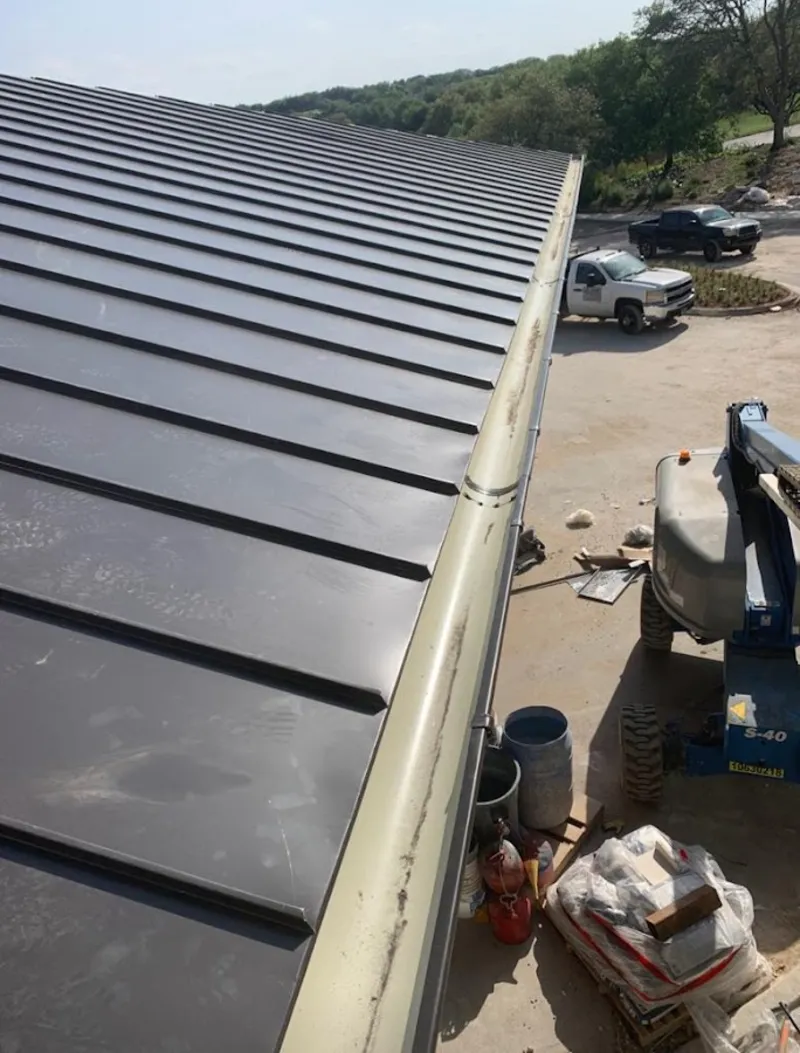 Standing seam panel and gutter detail on a metal roofing jobsite in Ashland
